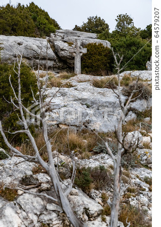 The sacred cross St.Pilon is on the mountain in cloudy weather, clouds over a valley, a dry grass, mountain over grotto of Mary Magdalene 64579207