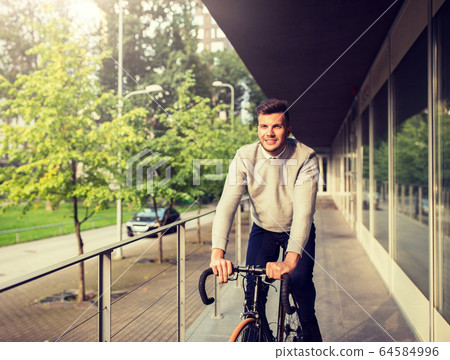 young man riding bicycle on city street young man riding bicycle on city street 64584996