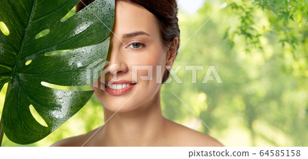 beautiful young woman with green monstera leaf beautiful young woman with green monstera leaf 64585158