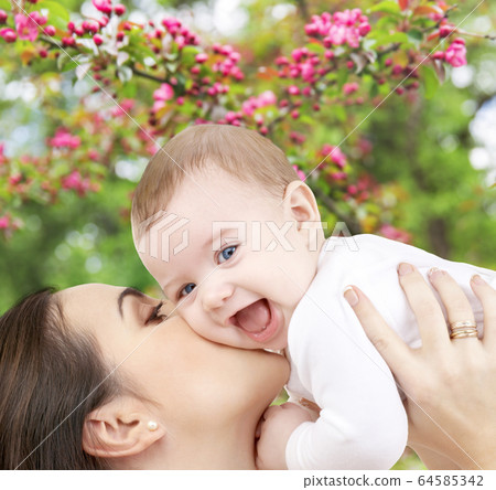 close up of mother kissing baby over garden 64585342