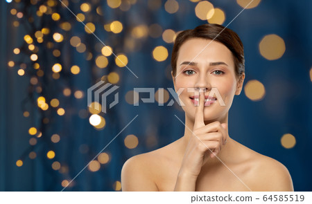 beautiful young woman holding finger on lips beautiful young woman holding finger on lips 64585519