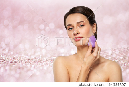 young woman with sponge applying makeup 64585807