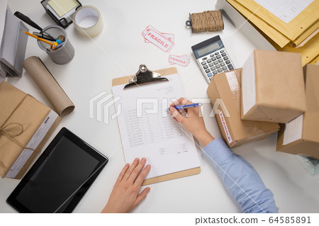 woman with parcels and clipboard at post office 64585891