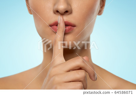 beautiful young woman holding finger on lips beautiful young woman holding finger on lips 64586071