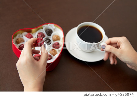 hands, candies in heart shaped box and coffee cup hands, candies in heart shaped box and coffee cup 64586074