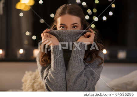 young woman in woolen sweater at home at night young woman in woolen sweater at home at night 64586296