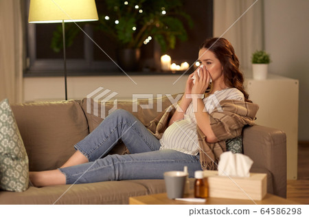 sick pregnant woman blowing nose at home sick pregnant woman blowing nose at home 64586298