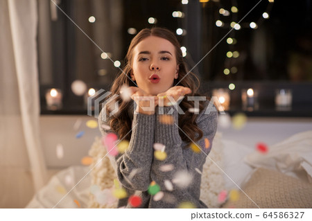 woman blowing confetti from her hands at home woman blowing confetti from her hands at home 64586327