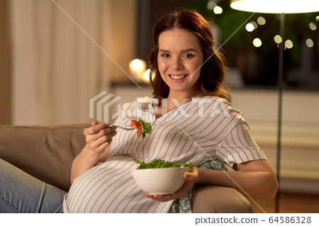 happy smiling pregnant woman eating salad at home happy smiling pregnant woman eating salad at home 64586328