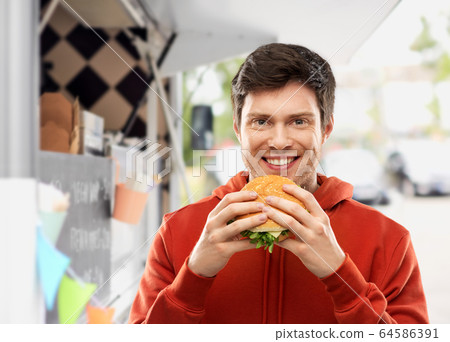 happy young man eating hamburger at food truck happy young man eating hamburger at food truck 64586391