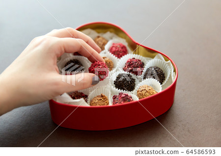 hand with candies in heart shaped chocolate box hand with candies in heart shaped chocolate box 64586593