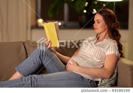 happy smiling pregnant woman reading book at home happy smiling pregnant woman reading book at home 64586599