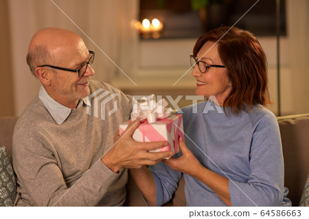 happy senior couple with gift box at home 64586663