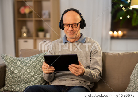senior man with tablet pc and headphones at home 64586673