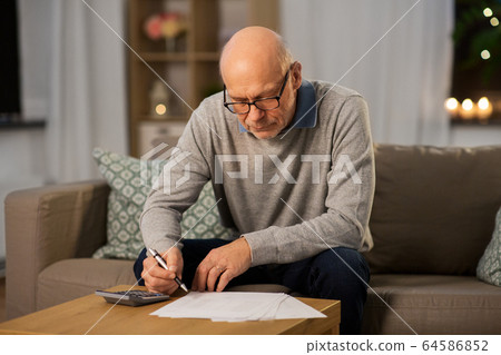 senior man with bills and calculator at home 64586852