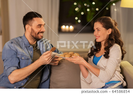 happy couple drinking tea with cookies at home 64586854
