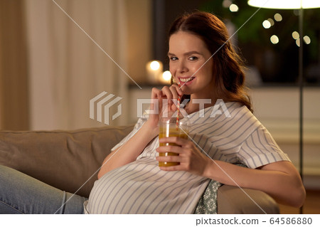 happy pregnant woman drinking juice at home 64586880