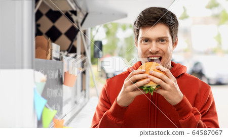 happy young man eating hamburger at food truck 64587067