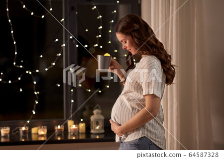happy pregnant woman drinking tea at home happy pregnant woman drinking tea at home 64587328