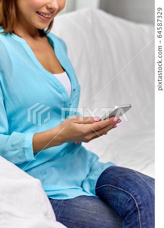 happy woman texting message on smartphone at home happy woman texting message on smartphone at home 64587329