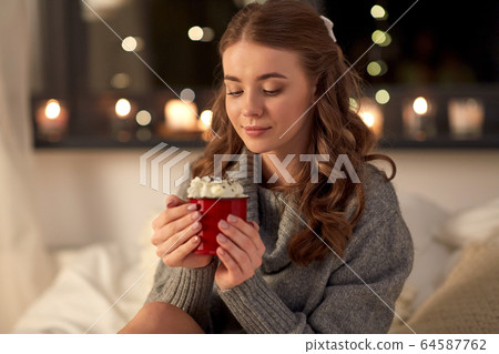 happy woman holding mug with whipped cream in bed happy woman holding mug with whipped cream in bed 64587762