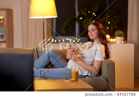 pregnant woman watching tv and eating wok at home pregnant woman watching tv and eating wok at home 64587766