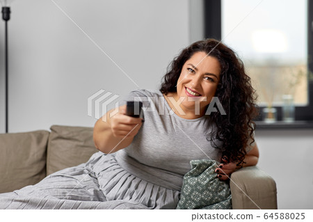 woman with remote control and watching tv at home woman with remote control and watching tv at home 64588025
