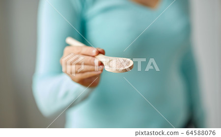 close up of woman with sea salt on wooden spoon 64588076