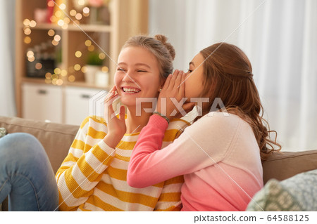 happy teenage girls gossiping at home 64588125