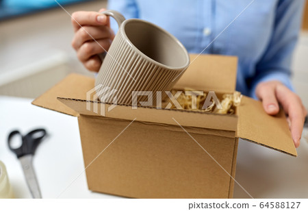woman packing mug to parcel box at post office woman packing mug to parcel box at post office 64588127