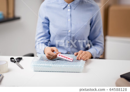 woman sticking fragile mark to wrap at post office woman sticking fragile mark to wrap at post office 64588128