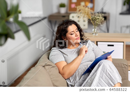 woman with clipboard and pen thinking at home woman with clipboard and pen thinking at home 64588322