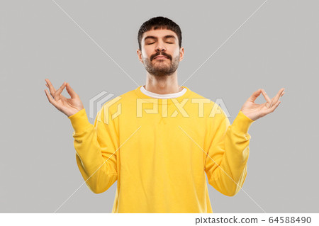 young man in yellow sweatshirt meditating young man in yellow sweatshirt meditating 64588490
