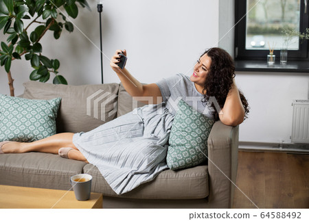happy woman taking selfie with smartphone at home 64588492