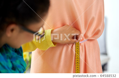 fashion designer measuring dress with tape measure 64588532