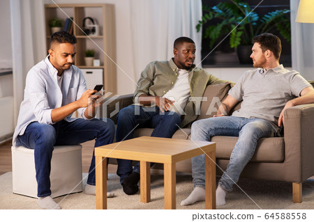 man using smartphone while friends talking at home 64588558