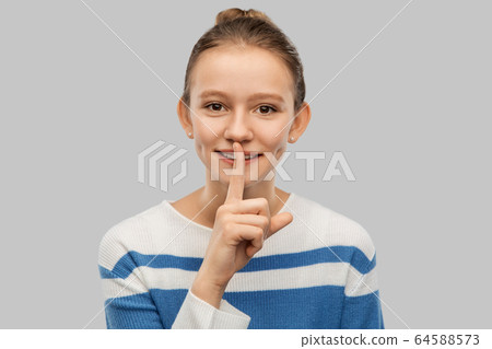 smiling teenage girl with finger on lips 64588573