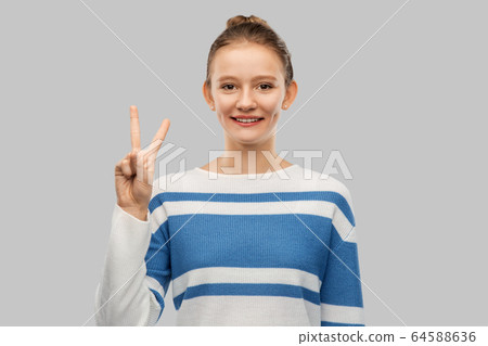 smiling teenage girl showing peace hand sign 64588636