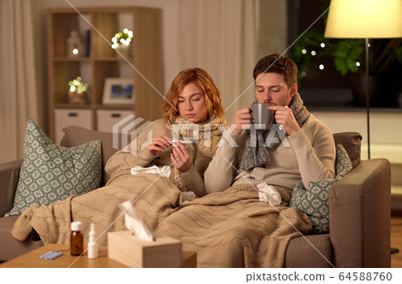 sick couple with thermometer and tea at home sick couple with thermometer and tea at home 64588760
