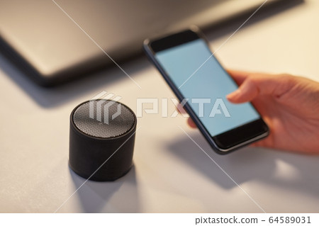 hand with smartphone and smart speaker at office hand with smartphone and smart speaker at office 64589031