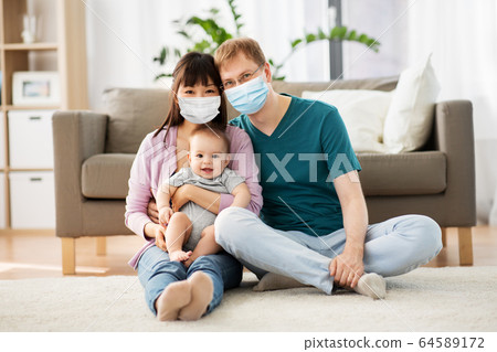 family with baby in medical masks at home family with baby in medical masks at home 64589172