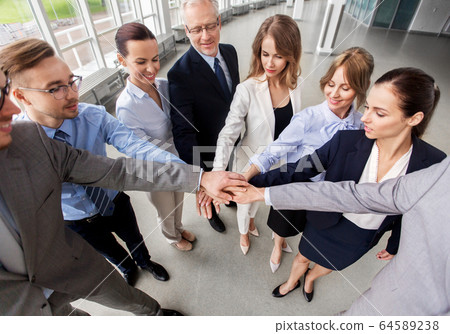 happy business people stacking hands at office 64589238