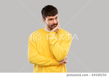 sad young man in yellow sweatshirt thinking sad young man in yellow sweatshirt thinking 64589250