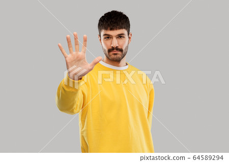 serious young man showing stop gesture 64589294