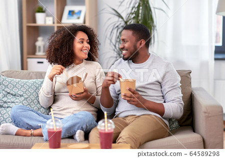 happy couple with takeaway food and drinks at home 64589298