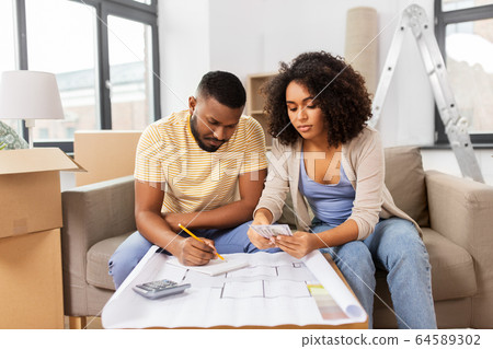 couple with blueprint counting money at home 64589302