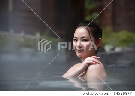 A woman enjoying an open-air bath 64589877