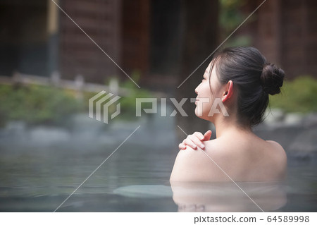 A woman enjoying an open-air bath 64589998