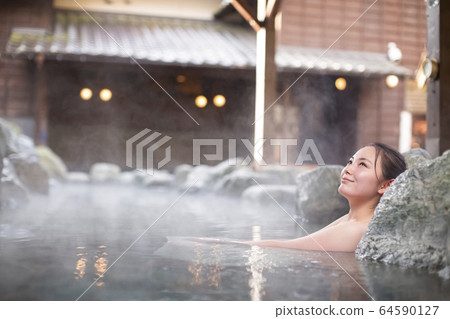 A woman enjoying an open-air bath 64590127
