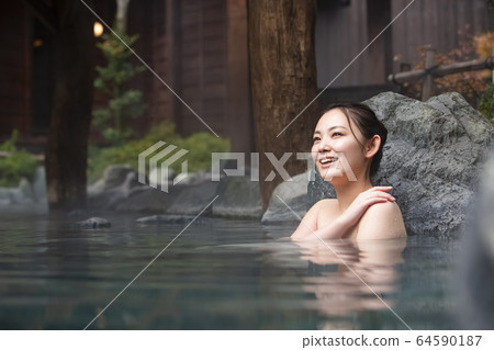 A woman enjoying an open-air bath 64590187